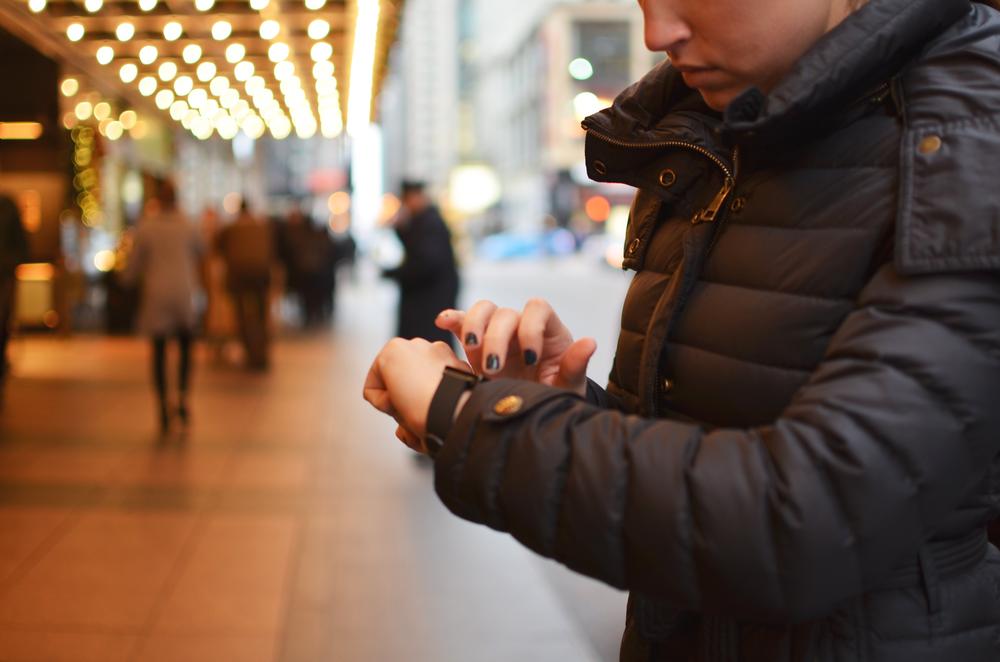Image of a person using an Android Wear smartwatch in an urban winter scene.