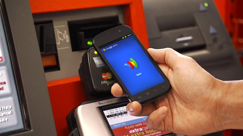 A promotional image of a person using tap-to-pay with an Android handset running Google Wallet in a retail store checkout.