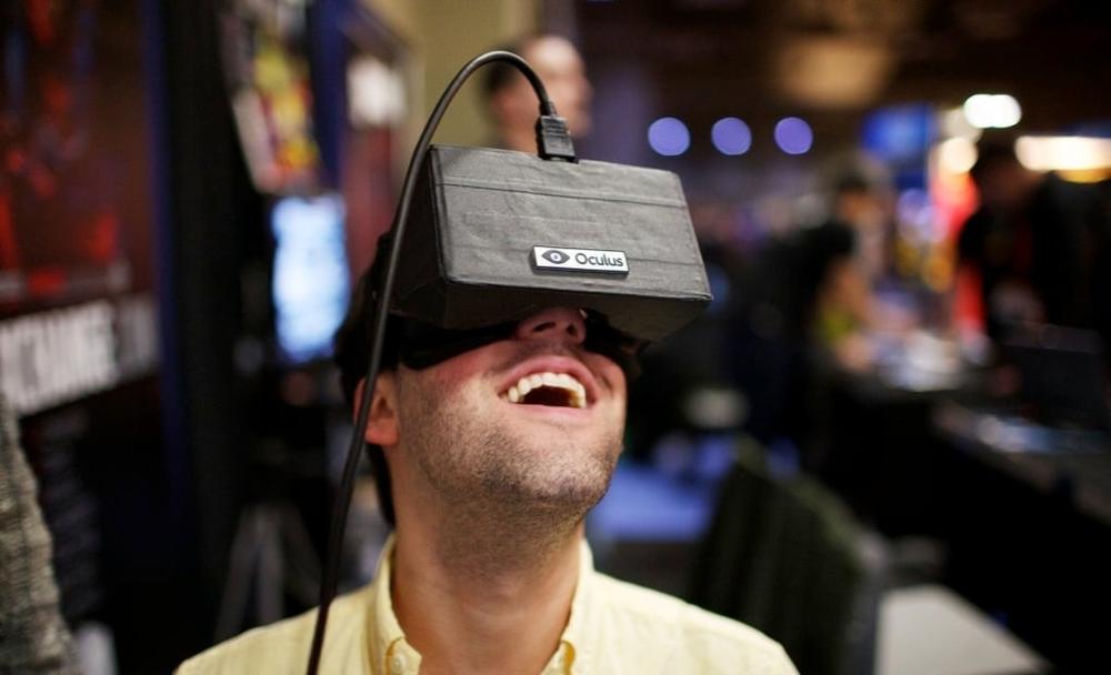 Photograph of a man wearing an Oculus Rift VR headset, looking up, and smiling.