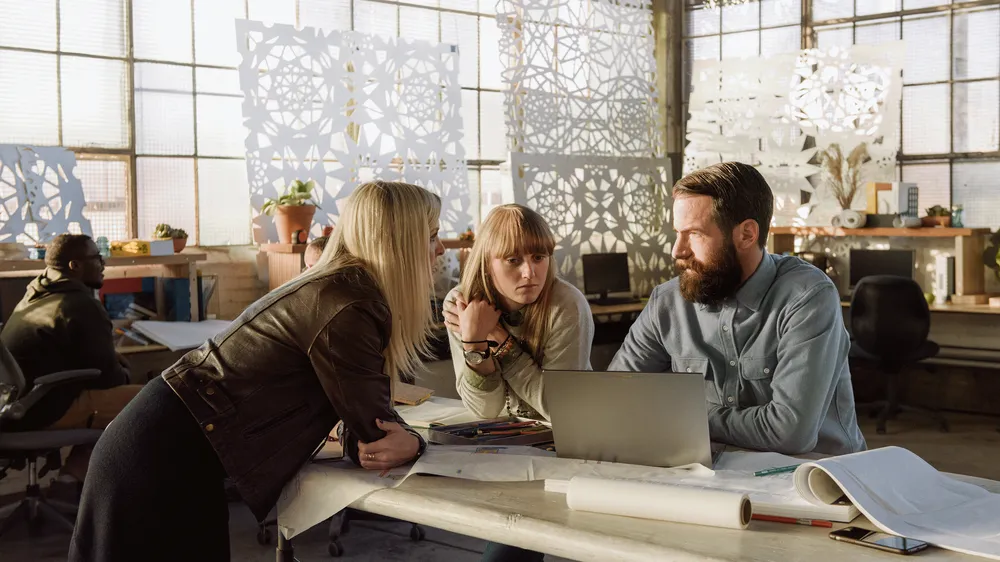 Photograph of three people collaborating in a workplace environment with a Chromebook Pixel laptop in front of them.